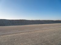 an empty, empty road with two vehicles parked in the dirt near a sand dune