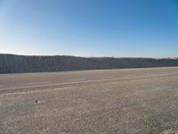 an empty, empty road with two vehicles parked in the dirt near a sand dune