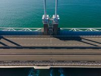 aerial view of an empty bridge over water with a city in the background and traffic on the road