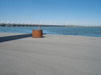 a concrete bench is standing in front of the water near a marina area with boats and buildings