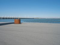 a concrete bench is standing in front of the water near a marina area with boats and buildings