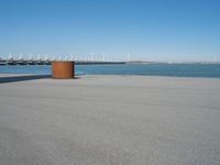 a concrete bench is standing in front of the water near a marina area with boats and buildings