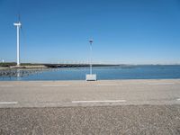 a street light and wind turbine on top of a pier near the water with boats in it