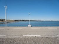 a street light and wind turbine on top of a pier near the water with boats in it