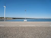 a street light and wind turbine on top of a pier near the water with boats in it