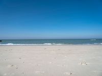 an open beach with a blue sky in the background and waves at the shore and a bright orange yellow sky
