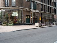 several bicycles on the street outside a restaurant in the city with buildings nearby and a bench