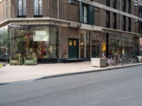 several bicycles on the street outside a restaurant in the city with buildings nearby and a bench