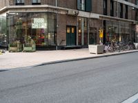 several bicycles on the street outside a restaurant in the city with buildings nearby and a bench