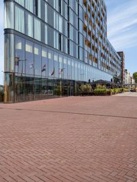 a large red brick sidewalk in front of some buildings with a reflection on the glass side