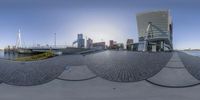 fisheye lens of an outdoor setting with boats docked in the harbor and buildings in the background