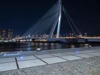 an illuminated pedestrian bridge crosses the water in a night scene of the city of london