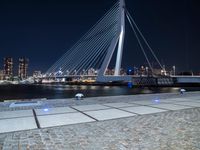 an illuminated pedestrian bridge crosses the water in a night scene of the city of london