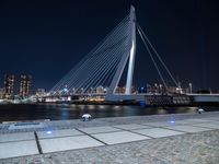 an illuminated pedestrian bridge crosses the water in a night scene of the city of london