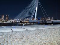 an illuminated pedestrian bridge crosses the water in a night scene of the city of london