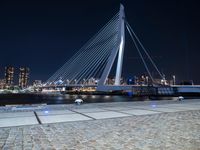 an illuminated pedestrian bridge crosses the water in a night scene of the city of london