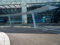 a man walks past an airport entrance with lots of windows and an arched sign for air traffic