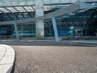 a man walks past an airport entrance with lots of windows and an arched sign for air traffic