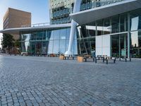 there is a black bench in the middle of a brick plaza with two buildings behind it