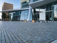 there is a black bench in the middle of a brick plaza with two buildings behind it