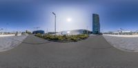 a street view with buildings in the background and the sun in the sky behind it