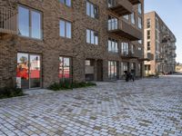 the bricked walkway between two buildings leads to several tables and benches along it's sides