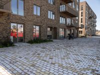 the bricked walkway between two buildings leads to several tables and benches along it's sides