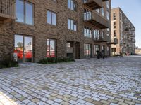 the bricked walkway between two buildings leads to several tables and benches along it's sides