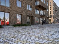 the bricked walkway between two buildings leads to several tables and benches along it's sides