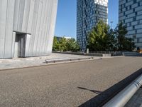 a skateboarder riding the rails outside of a building near other buildings and trees