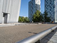 a skateboarder riding the rails outside of a building near other buildings and trees