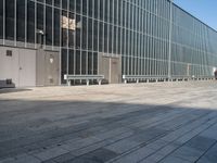 a skateboard sitting on the side of a building near a sidewalk with an empty bench