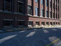 brick street in front of building with trees and buildings on it in shadow of the sun