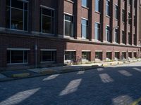 brick street in front of building with trees and buildings on it in shadow of the sun