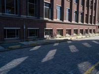 brick street in front of building with trees and buildings on it in shadow of the sun