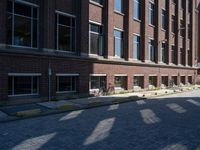 brick street in front of building with trees and buildings on it in shadow of the sun