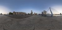 a fish eye lens image of the city in view from a brick area with a pedestrian bridge in the foreground