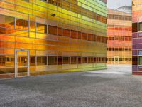 an abstractly colored building surrounded by a parking lot on asphalt, taken from the street