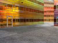 an abstractly colored building surrounded by a parking lot on asphalt, taken from the street