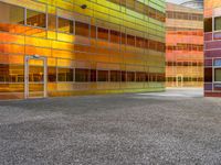 an abstractly colored building surrounded by a parking lot on asphalt, taken from the street