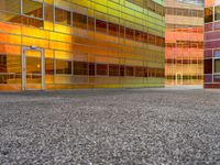 an abstractly colored building surrounded by a parking lot on asphalt, taken from the street