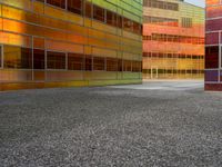 an abstractly colored building surrounded by a parking lot on asphalt, taken from the street