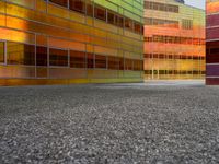 an abstractly colored building surrounded by a parking lot on asphalt, taken from the street