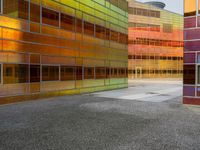 an abstractly colored building surrounded by a parking lot on asphalt, taken from the street