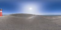 a 360 - view image of an empty beach with people on it and a lighthouse with a red and white pole