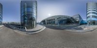 this is a 360 - angle view of some buildings in this city street with a bike rider crossing the street