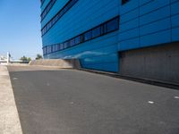 a skateboarder is going down the ramp by the street and blue building on a sunny day