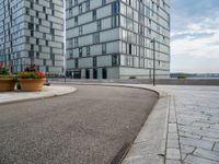 two tall buildings sitting next to each other on top of a sidewalk near a lake