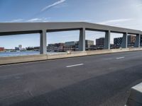 an empty city highway with a bridge and a few buildings in the background on a sunny day