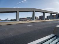 an empty city highway with a bridge and a few buildings in the background on a sunny day